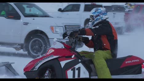 Close-up-of-skidoo-snowmobile-racers-in-slow-motion-with-snow-flying-over-one-rider