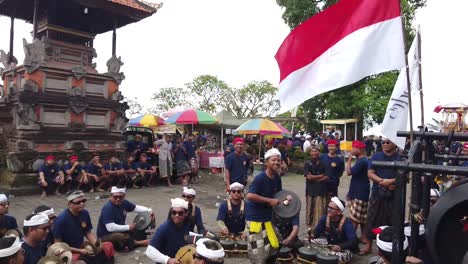 Gamelan-Musiker-Schlug-Bei-Der-Einäscherungszeremonie-Neben-Der-Indonesischen-Flagge,-Die-Im-Hindu-Tempel-Auf-Bali,-Indonesien,-Schwenkte,-Percussion-Bronzeinstrumente