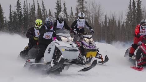 Snowmobile-racers-taking-off-at-starting-line-in-snowcross