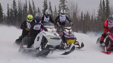 Corredores-De-Motos-De-Nieve-Despegando-En-La-Línea-De-Salida-En-Snowcross