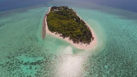 A-drone-glides-towards-a-distant-Heron-Island-as-we-see-it-is-surrounded-by-clear-green-and-blue-waters-and-reefs