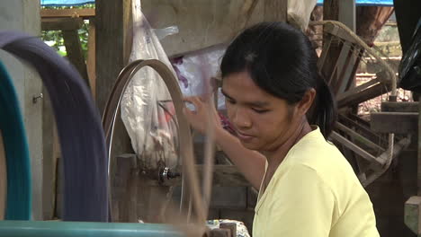 Mittlere-Aufnahme-Einer-Frau,-Die-In-Thailand-Traditionell-Einen-Faden-Spinnt