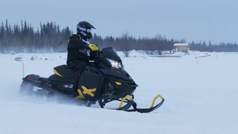 El-Corredor-De-Motos-De-Nieve-Toma-Una-Curva-Mientras-Mira-Hacia-Atrás-En-Una-Toma-Más-Cercana-En-Cámara-Lenta-Con-Panorámica