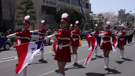 Women-are-marching-with-flags-at-the-parade-in-Kamamura,-Japan