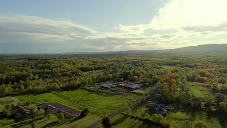 Drohne-Fliegt-über-Den-Wunderschönen-Goldenen-Stundenhimmel-In-Richtung-Eines-Hochzeitsortes-Auf-Dem-Ackerland-Im-Bundesstaat-New-York
