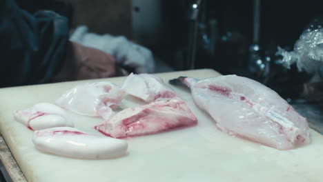 Fugu-Fisch-Auf-Weißem-Schneidebrett-Mit-Koch-Im-Hintergrund,-Der-Speisen-In-Der-Spüle-In-Kyoto,-Japan,-Zubereitet