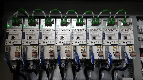 Statische-Nahaufnahme-Einer-Reihe-Industrieller-Wechselrichterantriebe-Mit-Flackernden-Grünen-LEDs-In-Einem-Schaltschrank-Einer-Laufenden-Maschine