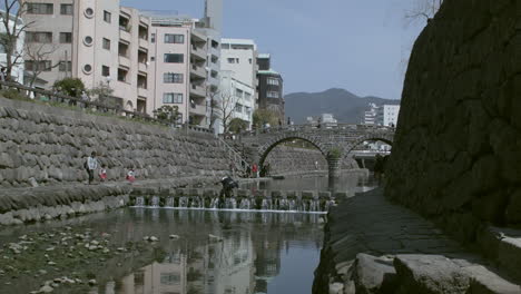 Static-shot-of-people-doing-activities---walking-across-Megane-bashi-'Spectacles-Bridge'-in-Nagasaki,-Japan