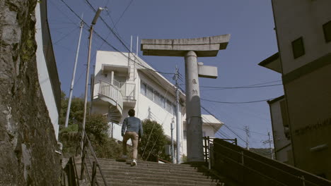 Male-walking-up-stairs-with-Sanno-Shrine-at-the-top-in-Nagasaki,-Japan
