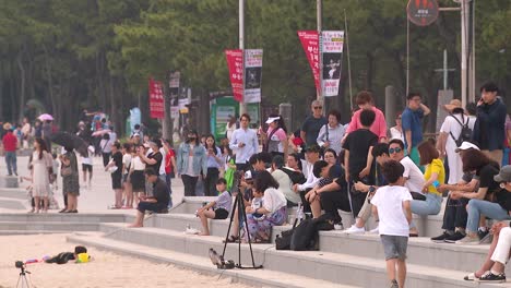 People-walking-along-the-footpath-in-Haeundae-Beach,-Busan,-South-Korea