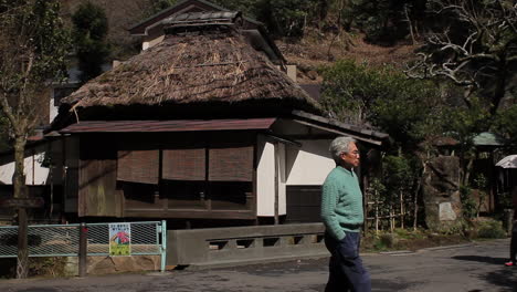 Thatched-building-in-Kamakura-with-people-walking-past,-Japan