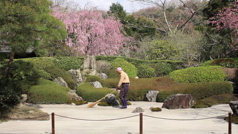 Gardener-raking-sand-in-Meigetsu-in-rock-garden,-Kita-Kamakura,-Kanagawa,-Japan