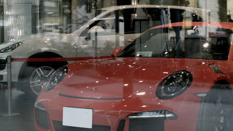 Orange-Porsche-in-dealership-window-in-Tokyo,-Japan