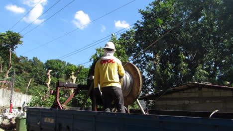 A-Lineman-Pulling-the-Transmission-Wire-in-a-Wooden-Spool,-Philippines