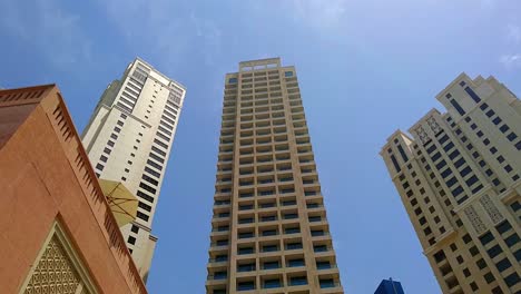 Vista-Exterior-Del-Día-En-Las-Torres-De-Apartamentos:-Edificios-En-El-Distrito-Deportivo-De-Dubai,-Emiratos-Árabes-Unidos,-árboles-Verdes-Y-Cielo-Azul