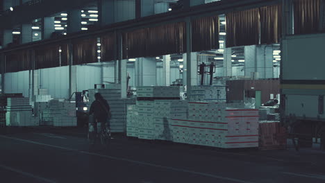 View-of-warehouse-loading-bay-entrance-as-man-on-machinery-hauls-boxes-of-tuna-fish-for-auction-in-darkness