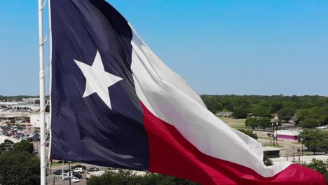 Eine-Nahaufnahme-Der-Texanischen-Flagge-Mit-Einem-Strahlend-Blauen-Himmel-Und-Einem-Blick-Auf-Die-Stadt-Wacos-Im-Hintergrund