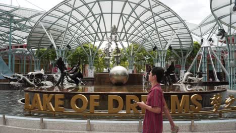 person-walks-past-lake-of-dreams-sentosa-island-singapore