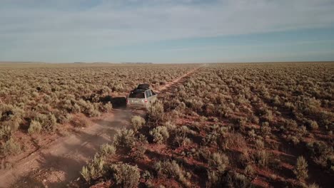 Vuelo-De-Drones-Siguiendo-Un-Todoterreno-Plateado-En-Una-Remota-Carretera-Desértica-De-Arizona