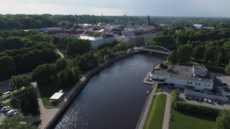 Flight-above-river-Emajogi-towards-old-town-in-Tartu,-Estonia