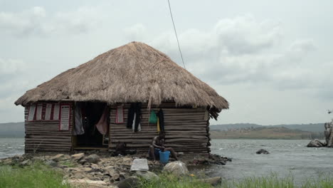 A-man-washes-clothes-outside-his-hut-on-the-Nile-River-in-Jinja,-Uganda
