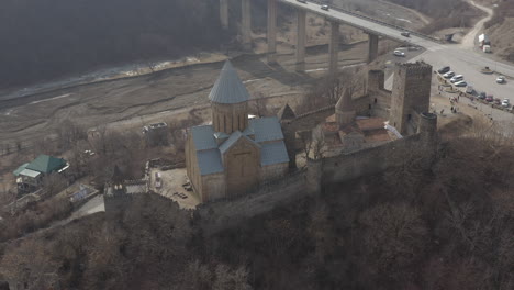 Sensational-establishing-view-above-Ananuri-fortress-complex,-bridge,-Aragvi-river-bed,-and-countryside,-aerial-pan