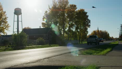Beautiful-shot-with-lens-flare-as-camera-tilts-down-and-pans-as-vehicles-drive-by-on-main-street-and-a-raven-flies-by-overhead