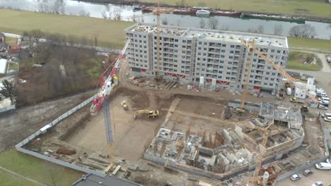 drone-fly-over-a-construction-site-with-high-crane-escavator-workers-building-new-residential-modern-quarter-area