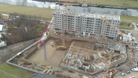 Drohne-Fliegt-über-Eine-Baustelle-Mit-Hochkran-Baggerarbeitern,-Die-Ein-Neues-Modernes-Wohnviertel-Bauen