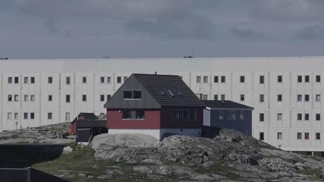 House-On-Rocky-Outcrop-With-Residential-Apartments-In-The-Background-In-Nuuk,-Greenland