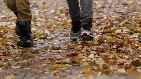 Nahaufnahme-Von-Kinderstiefeln,-Die-Im-Herbst-über-Nasse-Blätter-Laufen