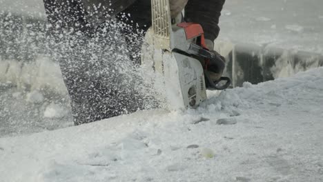 Close-up-of-chainsaw-cutting-blocks-of-ice-from-lake