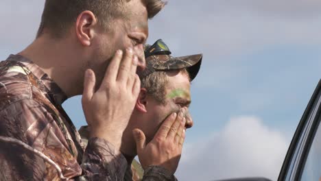 Two-duck-hunters-applying-camouflage-face-paint-before-hunting
