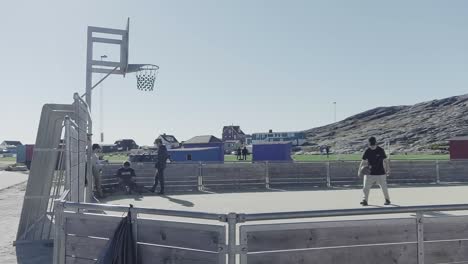 Jugendliche-Spielen-Basketball-Auf-Einem-Geschlossenen-Platz-Draußen-Im-Sonnigen-Nuuk,-Grönland
