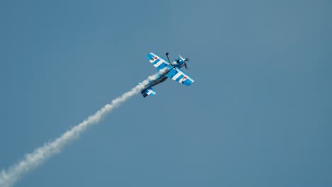 Closeup-aerobatic-stunt-plane-performing-aileron-roll-while-climbing-with-smoke-trail