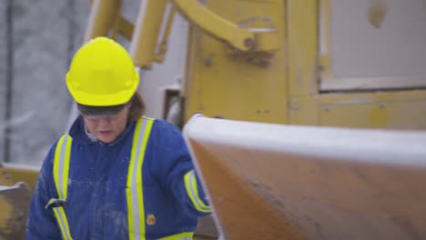 Female-heavy-equipment-operator-inspects-bucket-and-hydraulics-on-loader