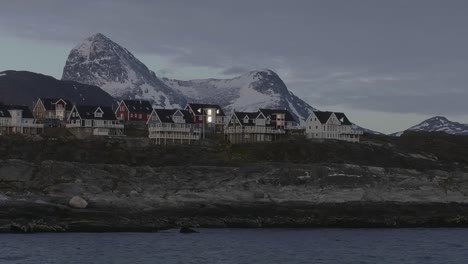 Paisaje-Nocturno-De-Casas-Nuuk-Con-Montañas-Al-Fondo