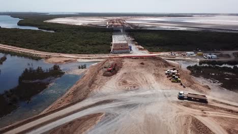 Toma-Aérea-De-Un-Camión-Conduciendo-En-Un-Sitio-De-Construcción-Cerca-De-Tierras-Húmedas