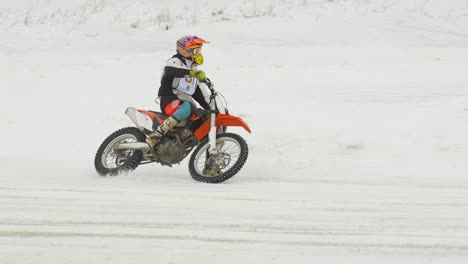 Great-slow-motion-profile-shot-of-motocross-racer-taking-corner-of-ice-track