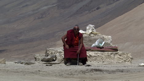 Lonely-nepalese-monk-seated-on-the-terrain-rocks-of-the-Himalayas,-wide-shot