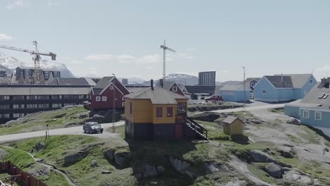 Colourful-Houses-On-Rocky-Hill-With-Construction-Cranes-In-The-Background-In-Greenland
