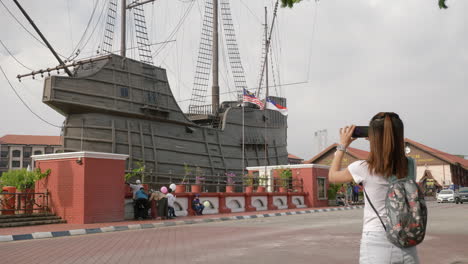 Panning-shot-of-girl-taking-picture-of-Flor-de-La-Mar,-a-ship-replica