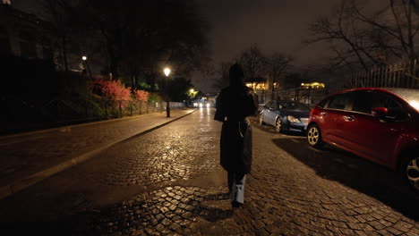 Mujer-Caminando-Por-Una-Calle-Adoquinada-Por-La-Noche-Usando-Un-Hijab,-Siguiendo-Detrás,-Toma-Cinematográfica-En-Cámara-Lenta-Media