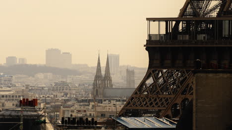 Hazy-morning-ins-Paris-France-Cityscape-with-part-of-Eiffel-Tower-in-foreground-and-city-buildings-and-church-in-distance