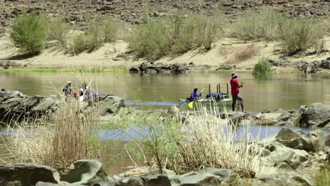 Kayakers-going-down-stream-enjoying-the-Fish-River-Canyon-in-Namibia---Long-wide-static-shot