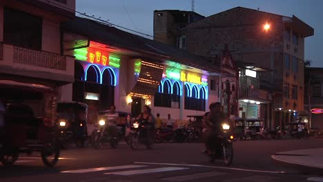 Busy-Traffic-Going-Past-Local-Bar-Lit-In-Evening-In-Iquitos,-Peru