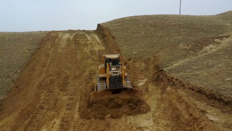 Bulldozer-at-a-construction-site-shovels-mountain-soil-into-a-heap
