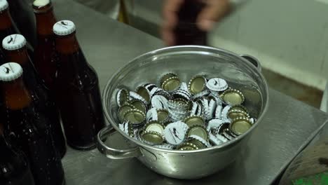 Hand-Picking-Up-Bootle-Cap-From-Bucket-On-Table-Next-To-Beverage-Drinks-In-Peru