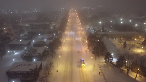 Schneepflug-Und-Autos-Fahren-Nachts-Die-Mit-Schnee-Und-Nebel-Bedeckte-Vorstadtstraße-Entlang,-Luftwagen