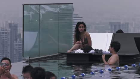 Pareja-De-Turistas-Disfrutando-Agradablemente-De-La-Piscina-Infinita-En-Marina-Bay-Sands-En-Singapur---Plano-Largo,-Estático,-Medio-Ancho